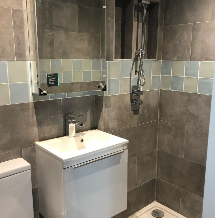 Grey tiled shower room with white vanity unit