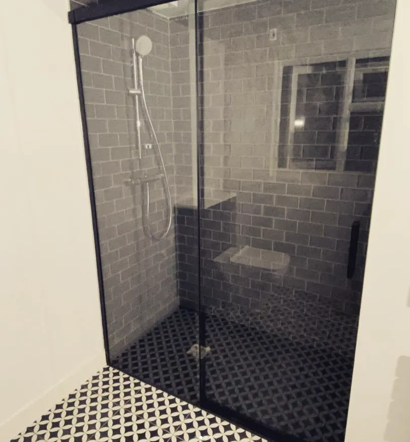 Walk in shower with black frame and patterned floor tiles